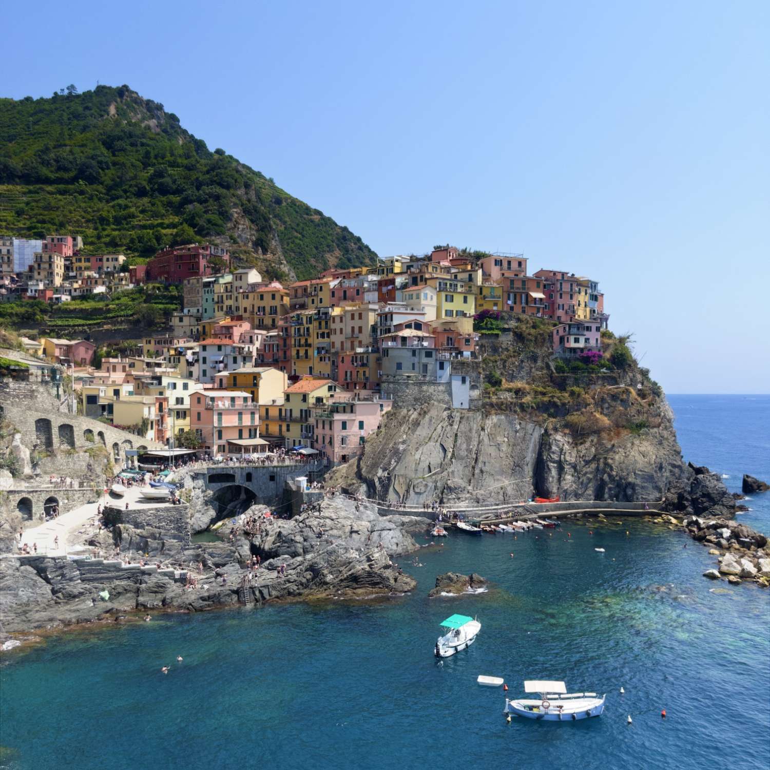 a photo of houses built haphazardly across a cliff, overlooking water gently waving in the wind